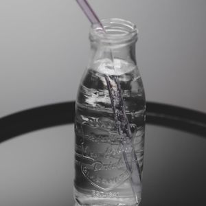 Glass water bottle on a dark surface with reflection